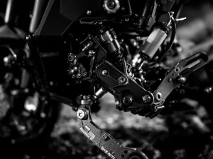 Adventure motorcycle rear suspension linkage system in black and white, showing shock absorber and pivot points mid-compression