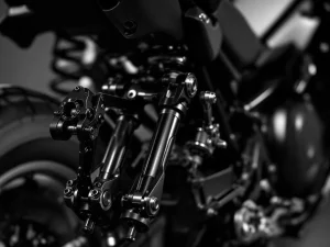 Close-up of adventure motorcycle rear suspension linkage system showing metallic pivoting arms and connecting rods in black and white