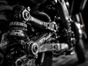 Adventure motorcycle rear suspension linkage with worn pivot bearings and connecting arms showing mechanical detail