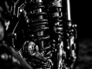 Adventure motorcycle rear suspension system with shock absorber, springs, and worn components in dramatic black and white