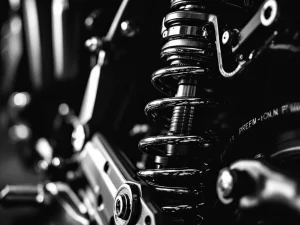 Adventure motorcycle rear suspension system with chrome spring and preload adjuster in dramatic black and white lighting