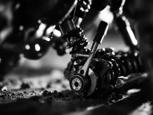 Close-up of adventure motorcycle suspension bushings and metal linkages with dramatic lighting in black and white