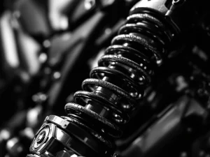 Progressive-rate motorcycle suspension spring with variable coil spacing on adventure bike shock absorber in dramatic lighting