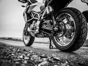 CFMOTO 450 MT adventure motorcycle on gravel road, low-angle black and white shot highlighting suspension and rugged stance.