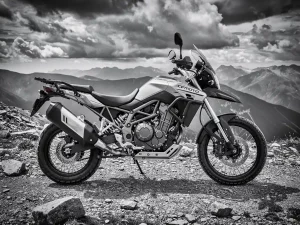 CFMOTO 450 MT adventure motorcycle on a rocky mountain trail, suspension forks and rear shock absorber visible, dramatic black and white contrast.