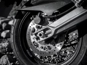 CFMOTO 450 MT rear brake disc and caliper assembly with sharp rotor teeth, machined metal textures, and adventure bike frame in background.