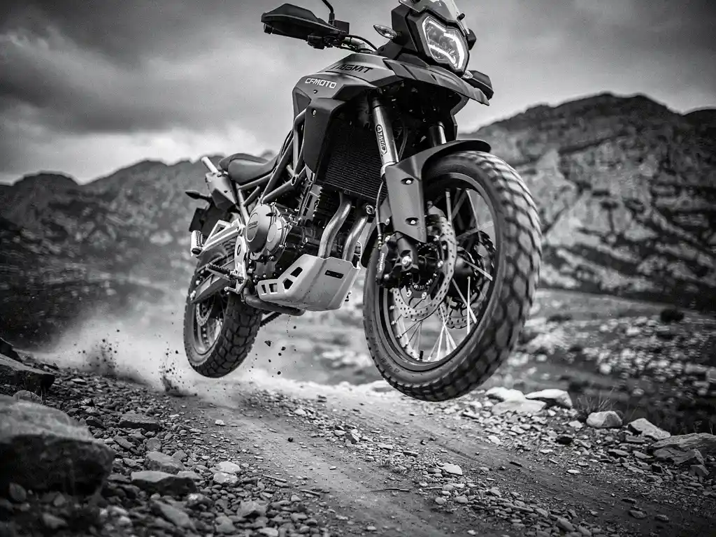 CFMOTO 450 MT adventure bike airborne over rocky dirt trail, suspension travel and fork seals sharply detailed, moody monochrome mountain backdrop.